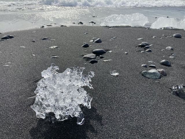 黒い砂浜の上にある透明で複雑な形をした氷の塊