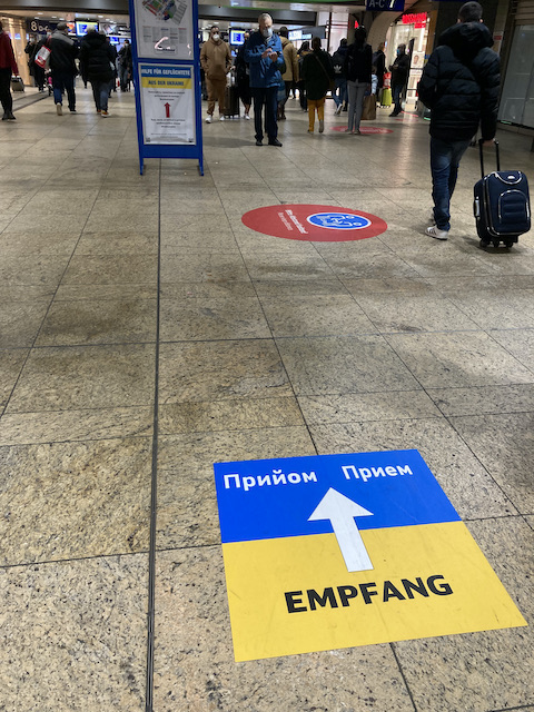 駅構内の床、ウクライナの国旗の色の上に、「受け入れ」とドイツ語とウクライナ語で書いてある