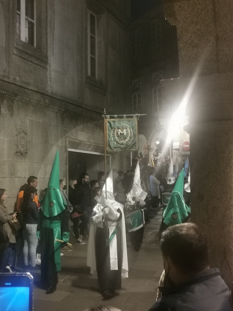 旗を持って行進する、目しか出ていない白と緑の装束を着た一団