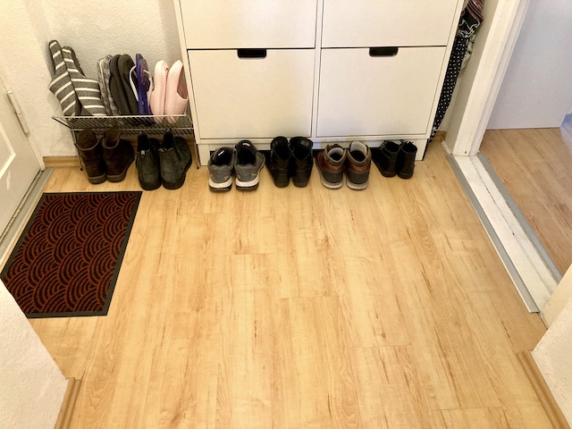 マットが敷かれたドアと、その横に並べられた靴箱と、靴とスリッパ
