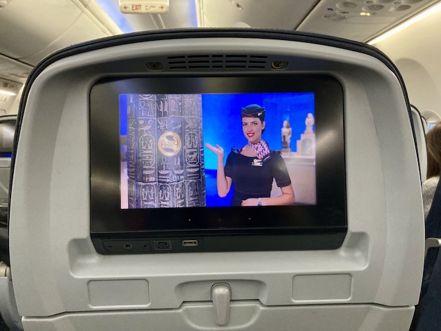 機内の座席モニターに映る女性CAと、うまく注意事項を盛り込んだヒエログリフの柱