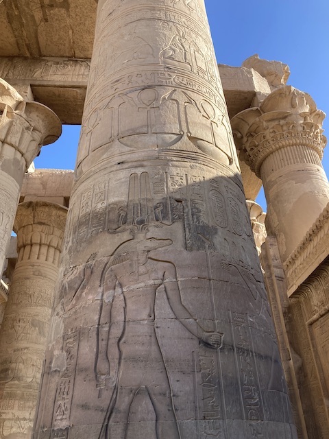 青空を背景にした野外の神殿の柱に刻まれた細かなレリーフ