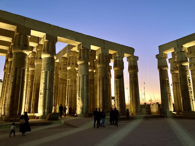 無数の巨大な円柱が並んだ回廊が、夕焼けの光に背後から照らされている