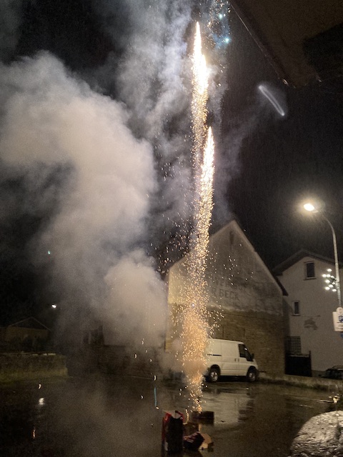 住宅の間の道路で空に向かって打ち上げられているロケット花火