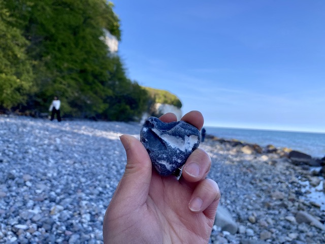 浜辺を背景に手に持っているハート型の石
