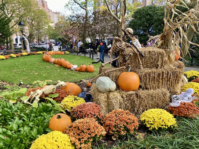 カボチャやオレンジ色の花が並べられ、積まれた藁の周りには人間と犬のガイコツが