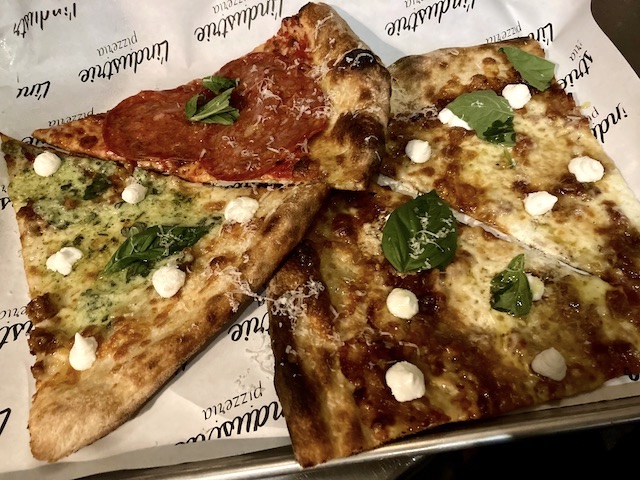 店のロゴが入った紙の上に並んでいる4切れのピザ