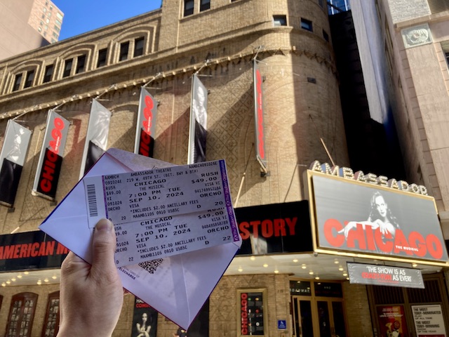 『シカゴ』の劇場の前で手にかかげて持っている2枚のラッシュチケット