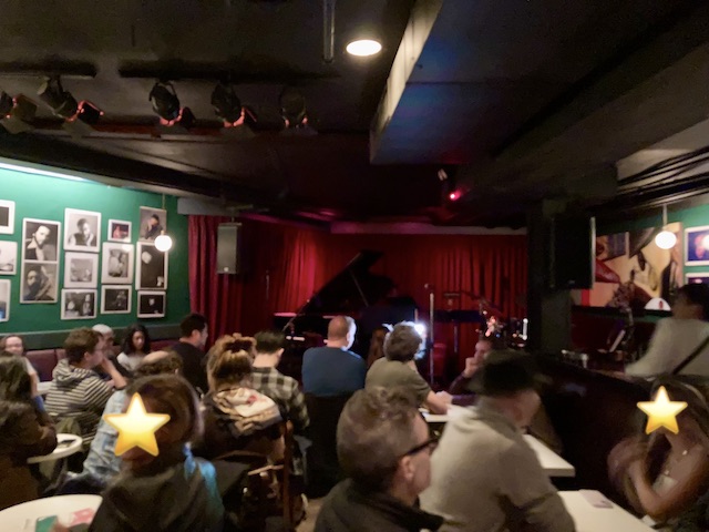 薄暗い店内に所狭しと並べられたテーブルに座る観客