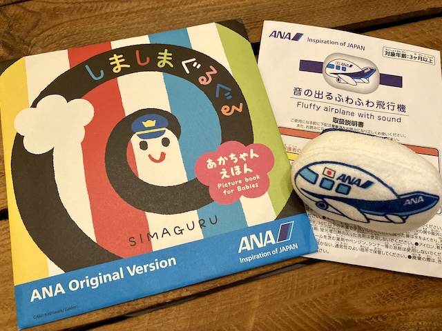 赤ちゃん用絵本「しましまぐるぐる」と、飛行機の形をしたぬいぐるみ