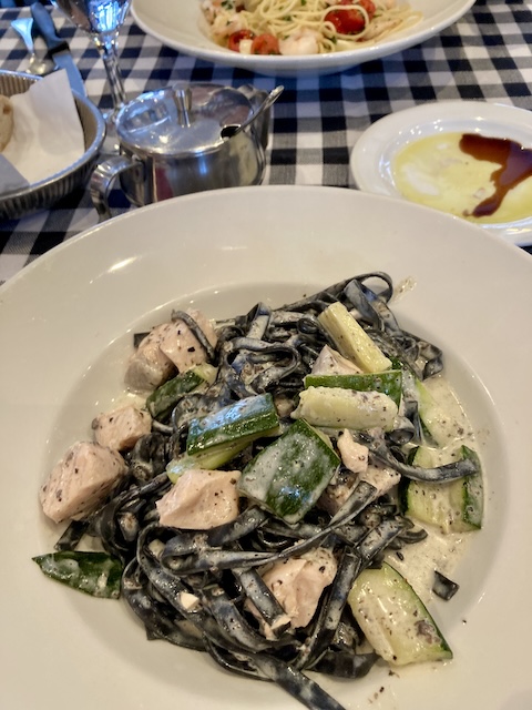 黒い幅広のパスタに、クリームソースがかかり、ズッキーニとサーモンがごろごろ入っている